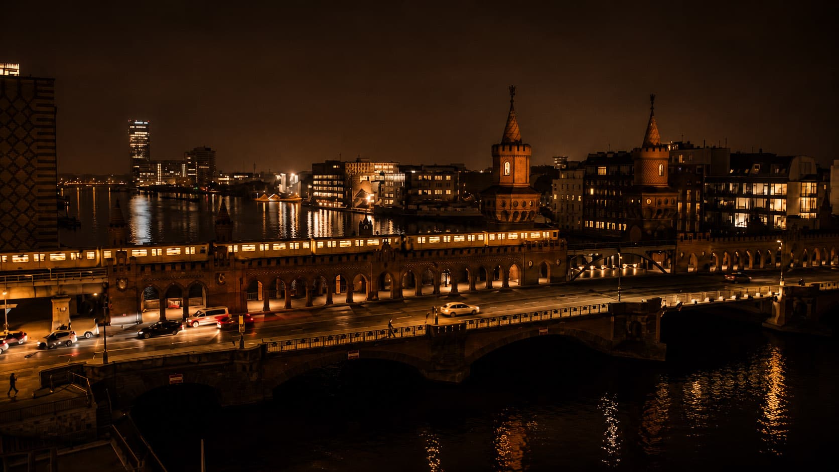 Die Oberbaumbrücke bei Nacht mit beleuchteter Skyline an der Spree